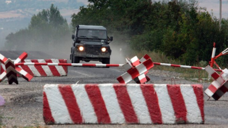 Barricades on the street and a car trying to pass.