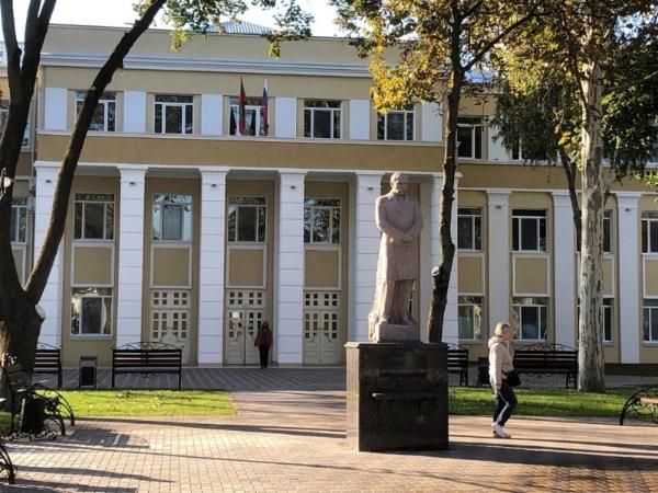 Sculpture of a standing man in front of a building.