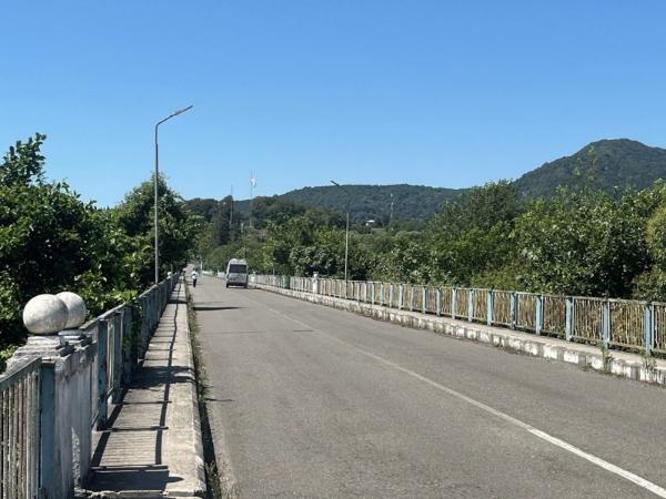 Bridge view with a man and a van crossing, mountains in the background.