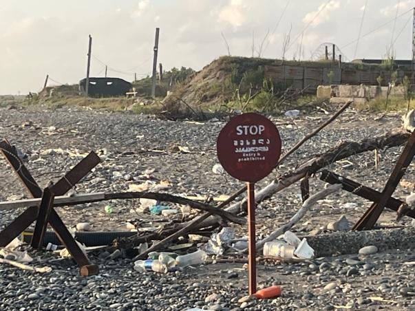 View of a beach showing a barbed fence and a stop sign.