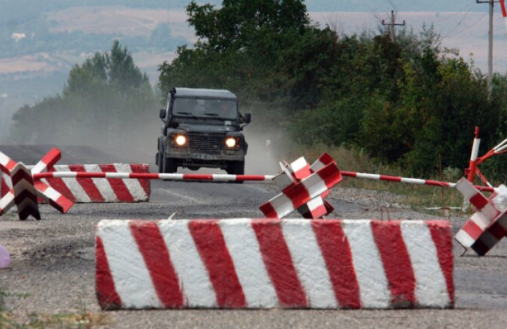 Barricades on the street and a car trying to pass.